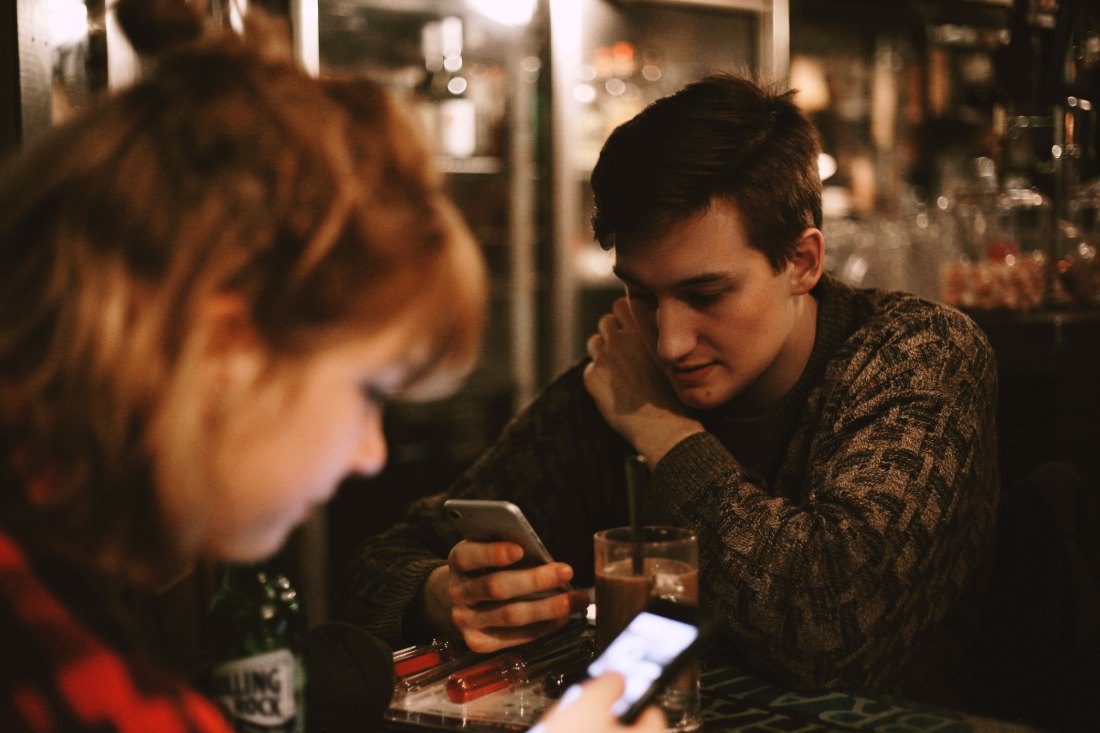 Boy and girl staring at their phone screens